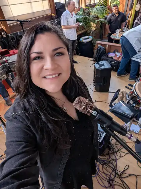 Laura Bravo smiling next to her microphone while the band sets up before a show