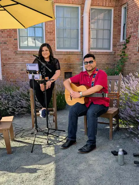 Laura Bravo performing as a duo on a brick patio surrounded by lavender