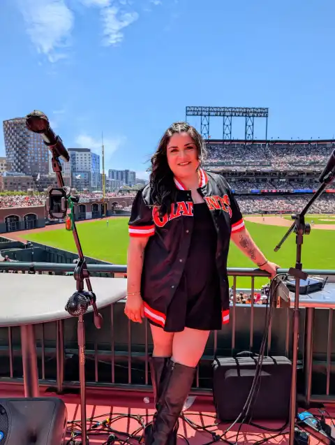 Laura Bravo on stage in a Giants jersey with a full house behind her at Oracle Park