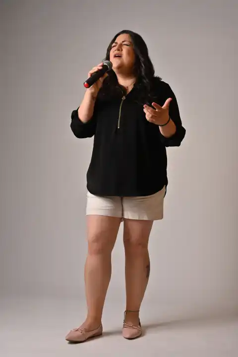 Laura Bravo singing into a handheld microphone during a studio session